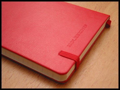 A red leather notebook on a wooden table