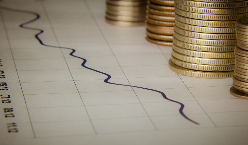 Stacks of coins beside a financial trend line on paper