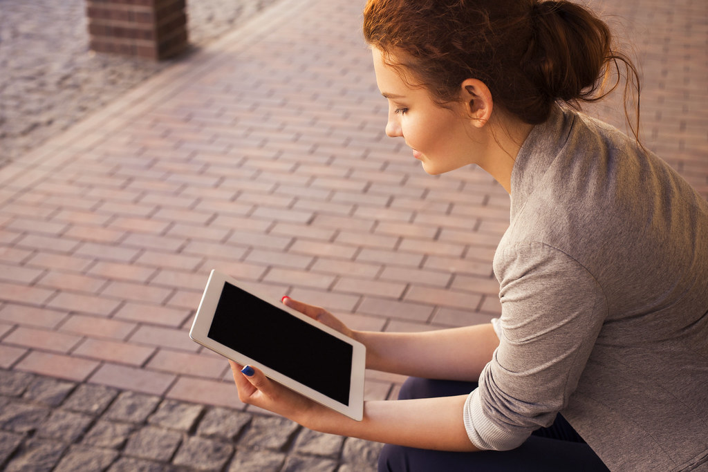 A young woman using a tablet outdoors